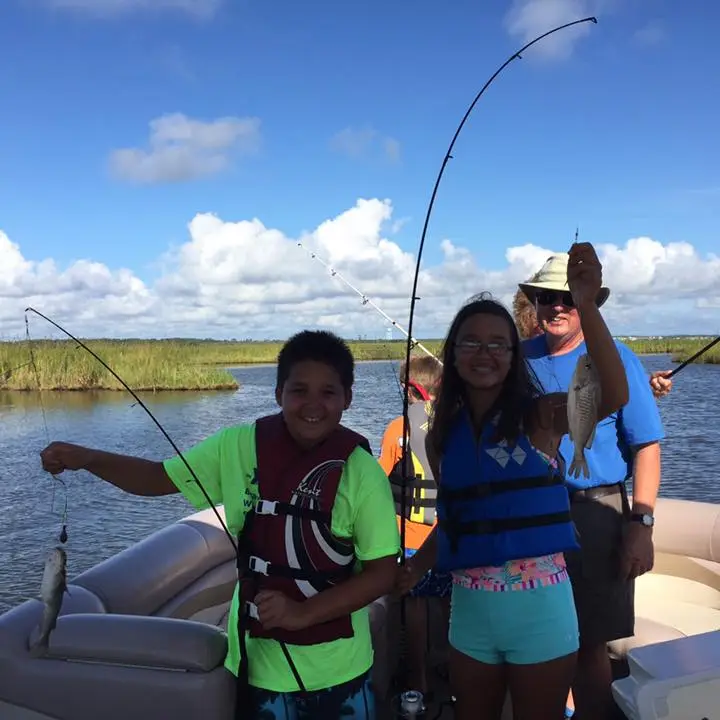 a group of people in a boat holding their caught fish