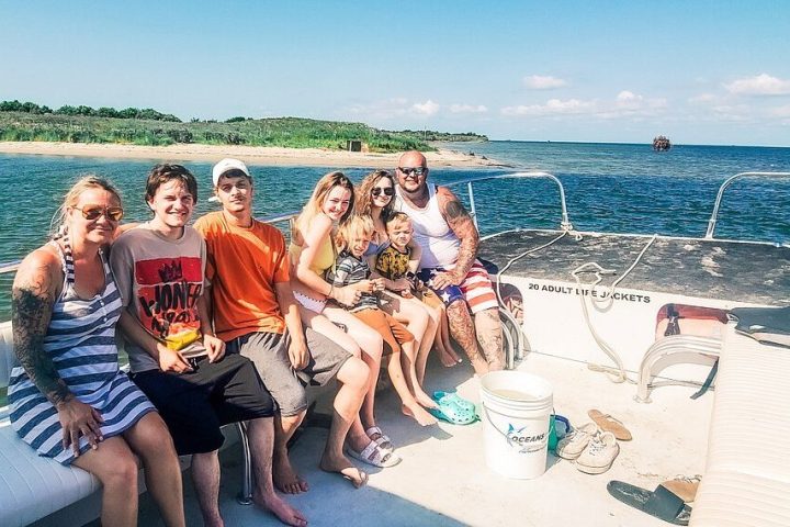 a group of people sitting on a boat next to a body of water